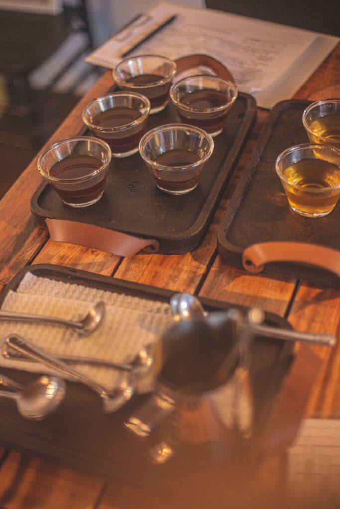An inviting coffee tasting setup featuring cups of coffee on a rustic wooden table with spoons and trays.
